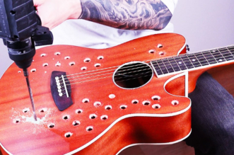 Bernth playing an acoustic guitar modified with dozens of holes