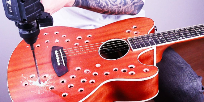Bernth playing an acoustic guitar modified with dozens of holes