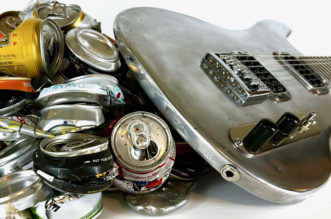Burls Art holding a fully functional electric guitar made from recycled aluminum cans