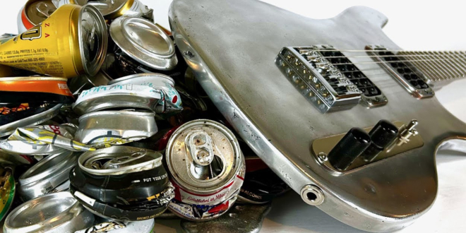 Burls Art holding a fully functional electric guitar made from recycled aluminum cans